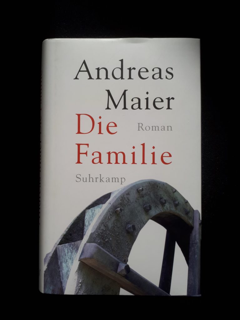 Cover zu "Die Familie" von Andreas Maier. Zu sehen ist der Ausschnitt eines Mühlrads in schwarz-weiß, der Hintergrund ist weiß. Der Buchtitel in roter Schrift darüber.